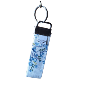 Fabric wristlet keychain featuring a pastel lavender and blue floral print with a silver key ring.