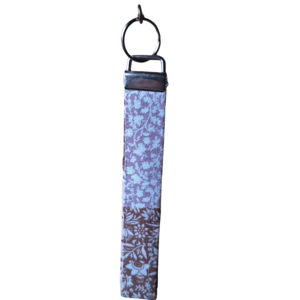 Fabric wristlet keychain with a soft pastel lavender and blue floral pattern attached to a metal hardware ring.