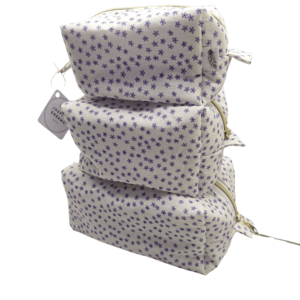 Three vertical stacking travel pouches in a white fabric featuring a soft blue and purple wildflower pattern.
